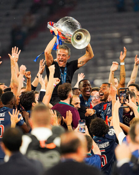 Luis Enrique levantando su segundo trofeo de la UEFA Champions League mientras el equipo celebra en un estadio lleno.